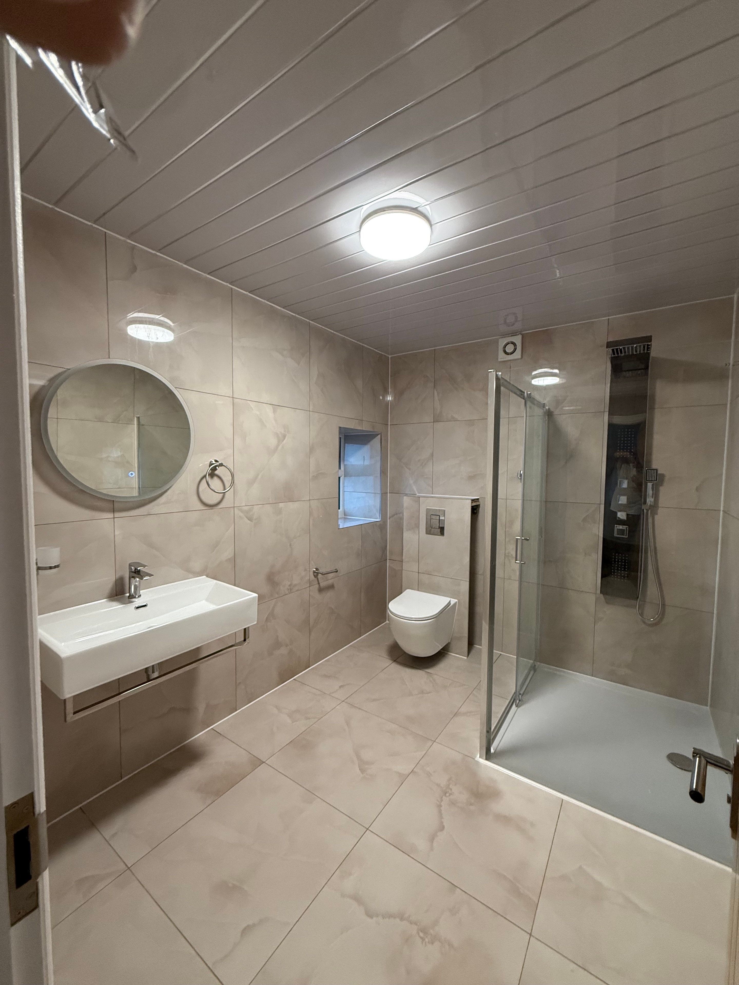 Completed bathroom renovation — dark bathtub with finished tiling and new fittings