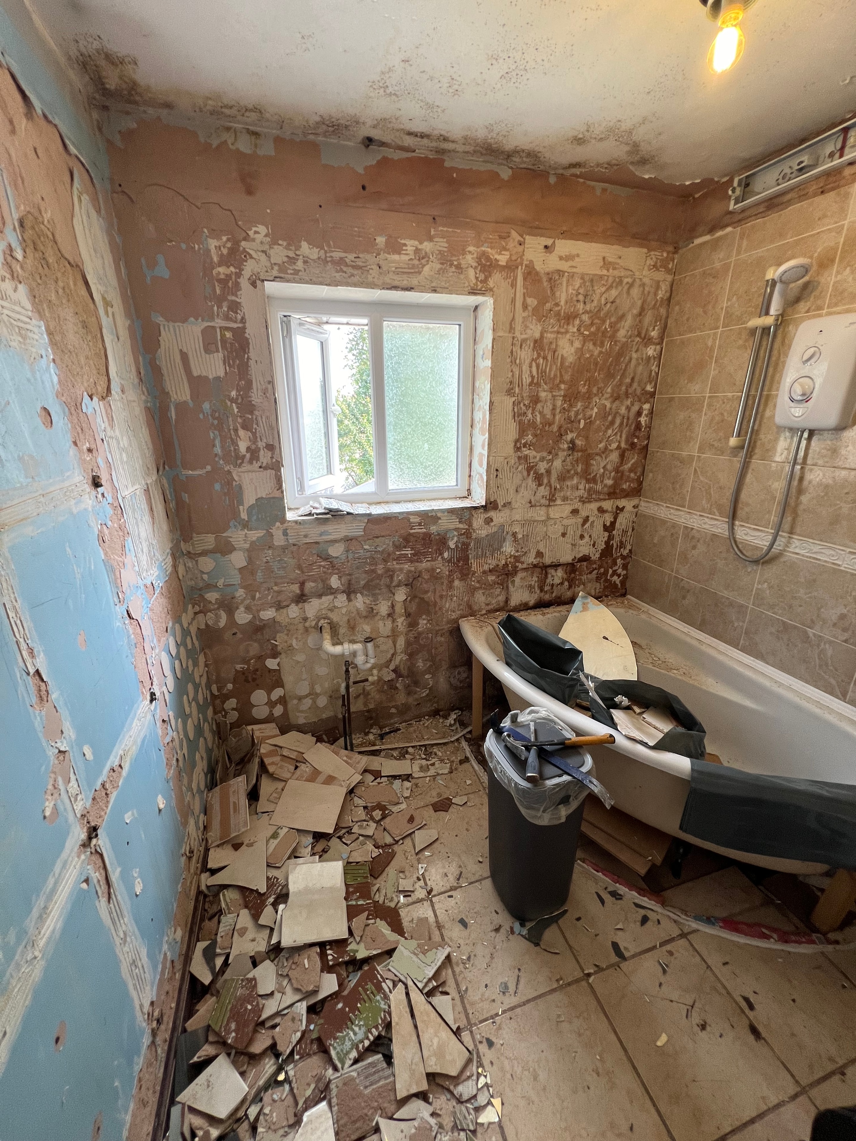 Completed bathroom renovation — dark brown bathtub with tiled surround and finished walls